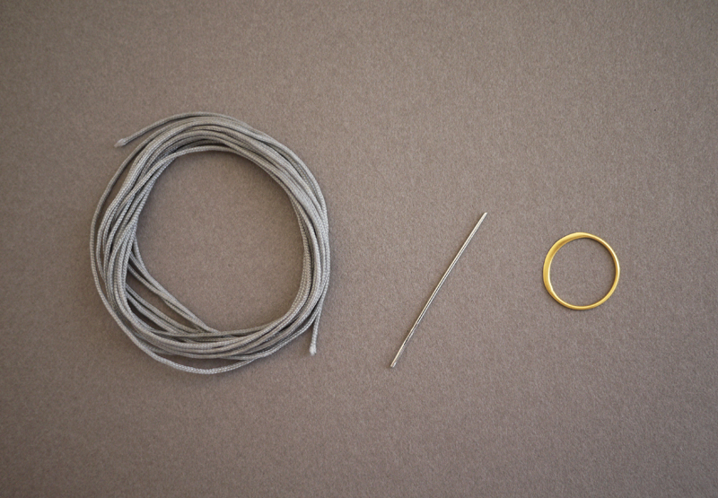 1. 1. Začneme umístěním kouzla (konektoru) na předpokládaný střed náramku. Konce nylonové šňůrky složíme k sobě a prostřihy, tak abychom dostali dva stejně dlouhé části. Každou z nich opӓť přeložíme napůl a konec s ohybem provlečeme kouzlem (konektorem) ze spodní strany nahoru. Přes očko protáhneme opačný konec a upevníme stažením. Zopakujeme na opačné straně. Oba prvky ukotví kouzlo (konektor) a zůstávají v klidu.