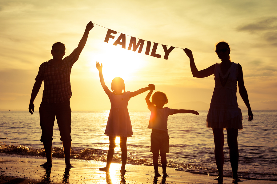 Happy family standing na pláži at the sunset time. Parents hold in the hands inscription